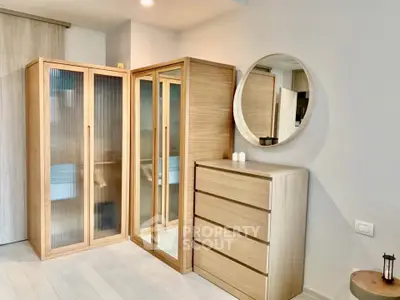 Modern bedroom with stylish wooden wardrobe and round mirror