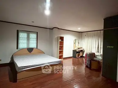 Spacious bedroom with wooden flooring and modern furniture