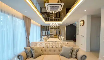 Luxurious modern living room with elegant decor and open dining area, featuring plush sofa and stylish lighting.