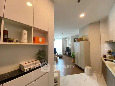 Modern open-layout kitchen and living area with stylish cabinets and bright lighting.