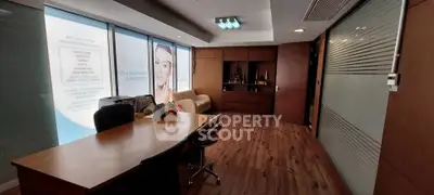Modern office space with wooden flooring and glass partitions, ideal for professional meetings.