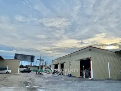 Spacious industrial warehouse with ample parking and open sky view.