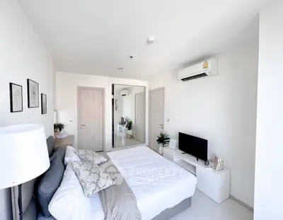 Modern bedroom with minimalist decor, featuring a comfortable bed, air conditioning, and a sleek TV setup.