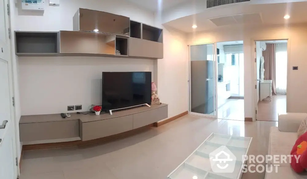 Modern living room with sleek TV unit and glass coffee table in stylish apartment