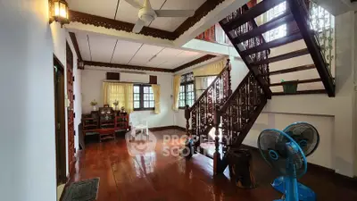 Charming living room with wooden floors and elegant staircase in a cozy home