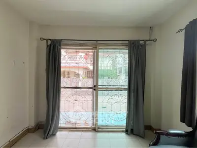 Spacious room with large window and elegant curtains, offering a view of the outdoor area.