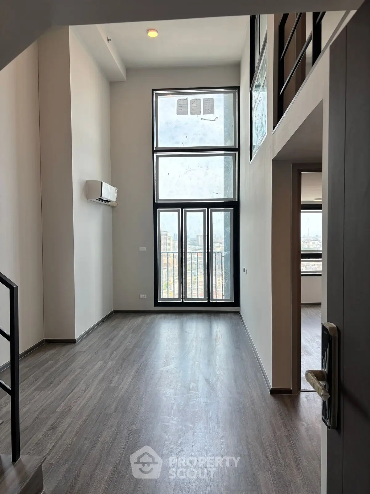 Modern loft-style living room with high ceilings and large windows