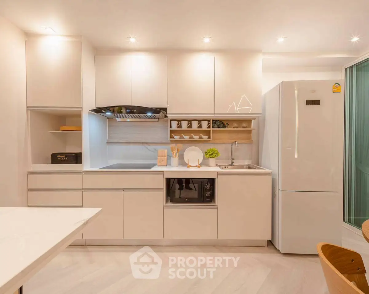 Modern kitchen with sleek cabinetry and appliances, featuring a spacious fridge and stylish lighting.