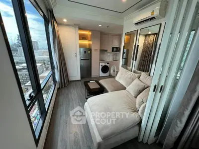Modern living room with city view, featuring cozy sofa and integrated kitchen appliances.