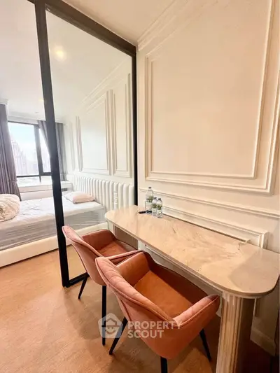 Elegant bedroom with stylish desk and chairs, featuring a large window with city view.
