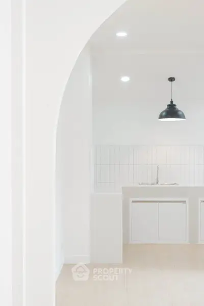 Minimalist kitchen with white cabinetry and modern pendant light