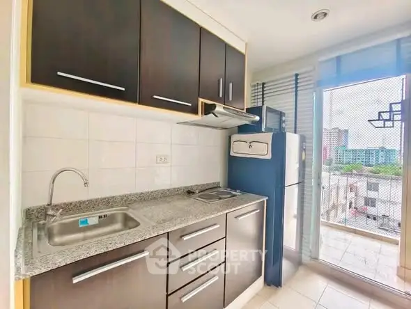Modern kitchen with sleek cabinets and balcony view in urban apartment