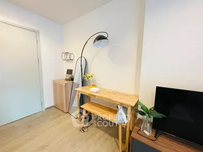 Modern living room corner with stylish furniture and decor, featuring a sleek floor lamp and a flat-screen TV.