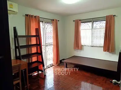 Cozy bedroom with wooden flooring and natural light from two windows