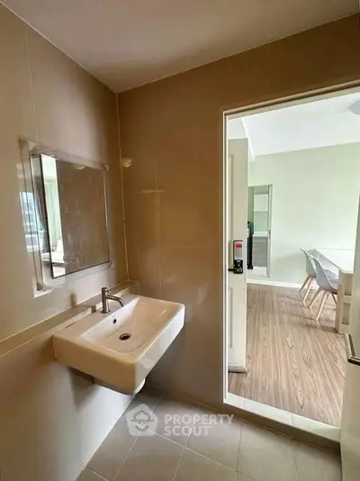 Modern bathroom with sleek sink and view into a bright dining area, showcasing contemporary design.