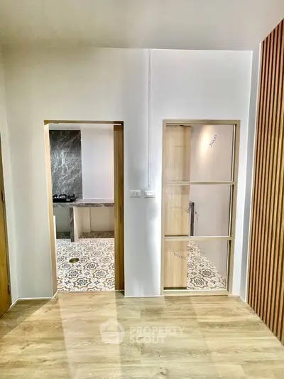Modern interior with stylish kitchen and wooden accents, featuring elegant tile flooring and sleek design.