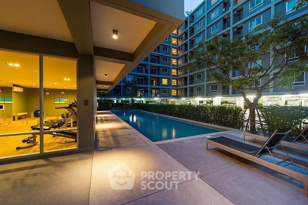 Modern apartment complex with pool and gym facilities at dusk.