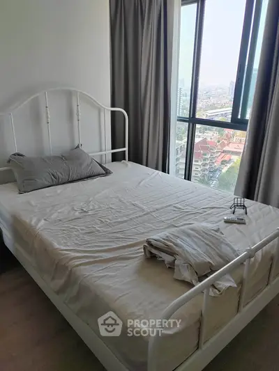 Cozy bedroom with large window offering stunning city views, perfect for urban living.