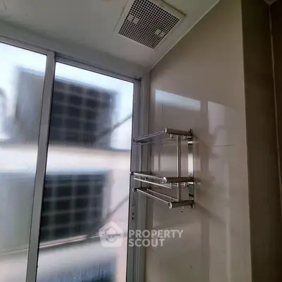 Modern bathroom with sleek towel rack and frosted glass window for privacy.