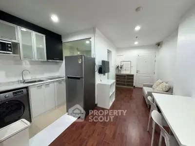 Modern open-layout kitchen and living area with sleek appliances and wooden flooring.