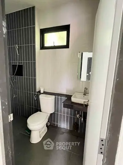 Modern bathroom with sleek design and contemporary fixtures, featuring a shower and stylish tiling.
