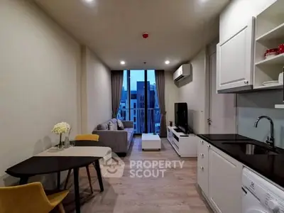 Modern living room with open kitchen and city view balcony, featuring sleek furniture and bright lighting.