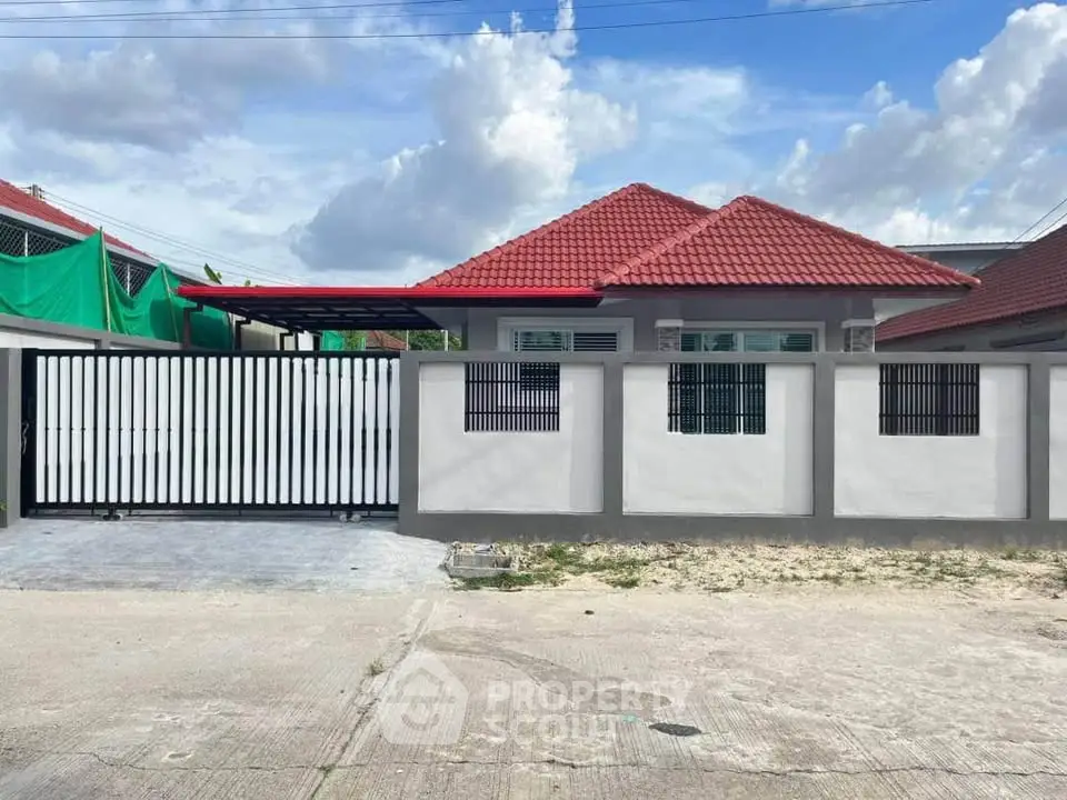 Charming single-story house with red roof and gated driveway, perfect for family living.