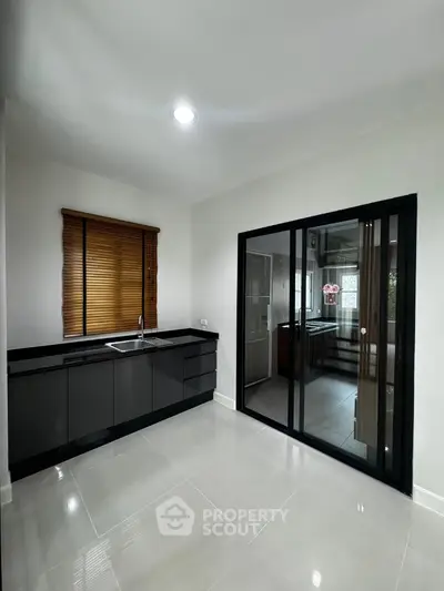 Modern kitchen with sleek black cabinetry and sliding glass door