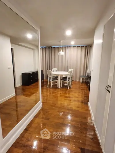 Spacious living room with polished wooden floors and elegant dining area.