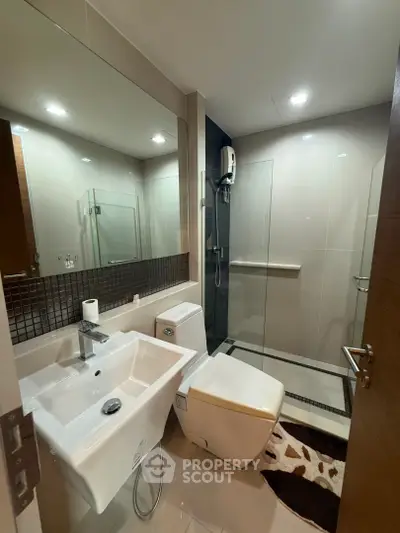 Modern bathroom with sleek fixtures and glass shower enclosure in a contemporary apartment.