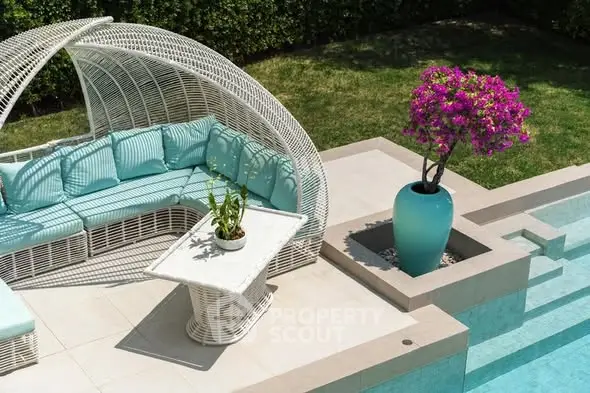 Luxurious outdoor pool area with stylish wicker seating and vibrant potted plant, perfect for relaxation.