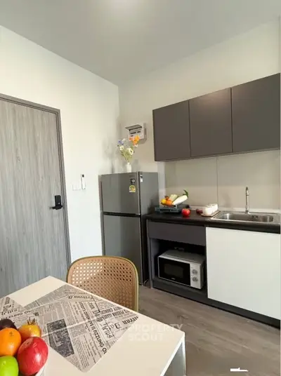 Modern kitchen with sleek cabinets, stainless steel fridge, and cozy dining area.