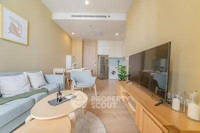 Modern living room with stylish furniture and open layout, featuring a large TV and dining area.