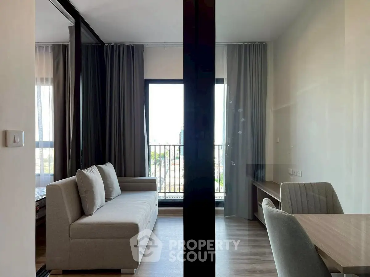 Modern living room with stylish sofa and dining area, featuring floor-to-ceiling windows and elegant curtains.