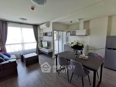 Modern living room with dining area and natural light, featuring stylish furniture and open layout.