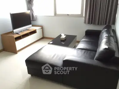 Modern living room with sleek black leather sofa and flat-screen TV
