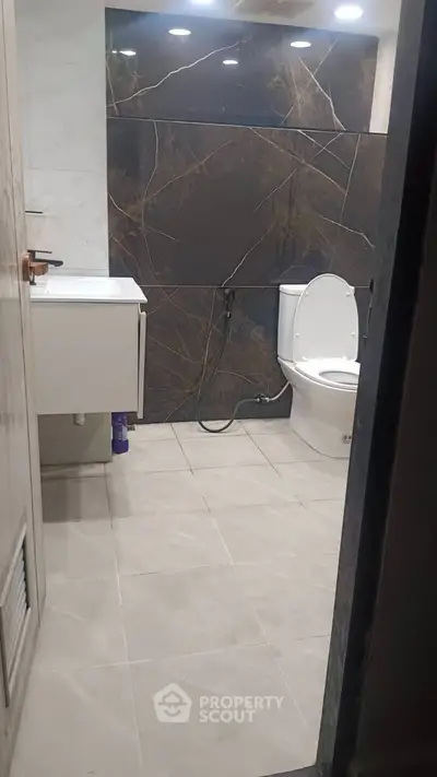 Modern bathroom with sleek design and elegant tile work, featuring a contemporary toilet and vanity.