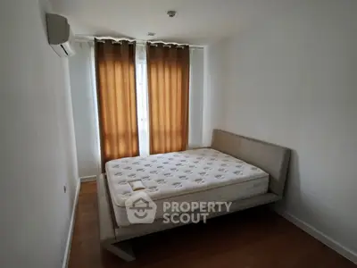 Minimalist bedroom with modern bed and air conditioning, featuring warm lighting and wooden flooring.