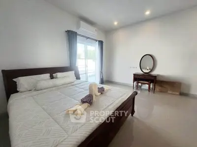 Spacious bedroom with elegant decor and natural light, featuring a large bed and stylish vanity.