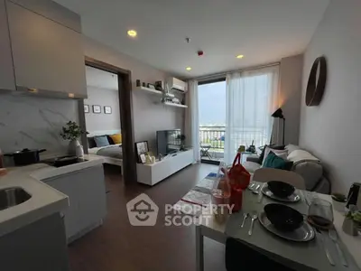 Modern open-plan living room with kitchen and balcony view, featuring stylish decor and natural light.