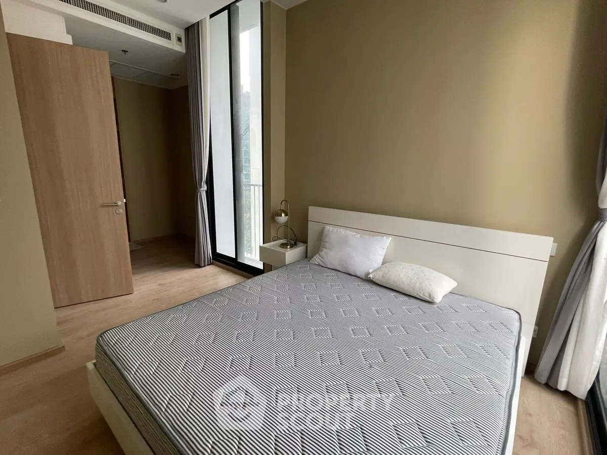 Modern bedroom with large window and stylish decor in a contemporary apartment.