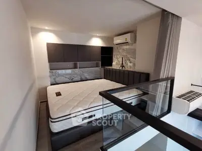 Modern bedroom with stylish decor and glass railing, featuring a comfortable bed and air conditioning unit.