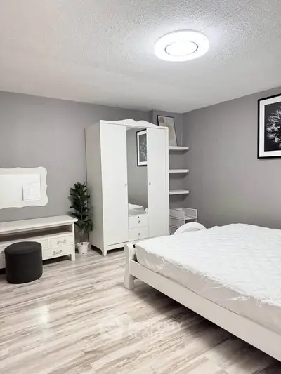 Modern bedroom with white furniture and stylish decor in a cozy apartment.