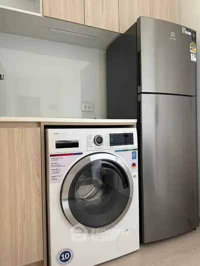 Modern kitchen with sleek appliances including washing machine and fridge, perfect for urban living.