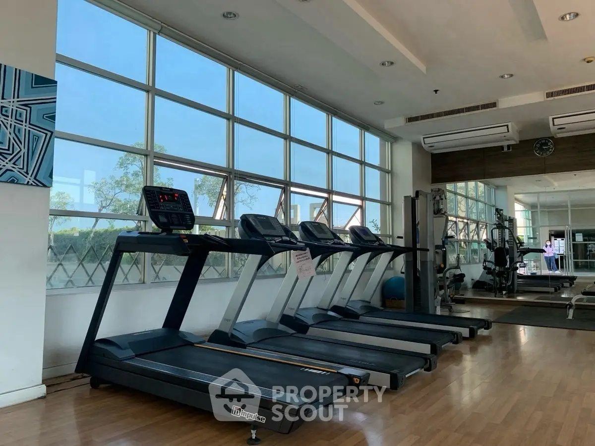 Spacious gym with modern treadmills and large windows offering natural light.