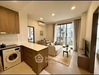 Modern open-plan living room with kitchen and balcony view in stylish apartment.