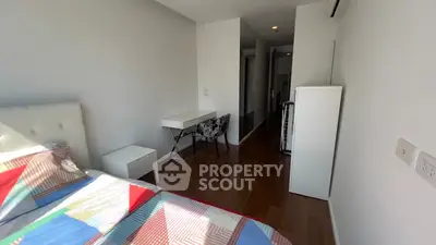 Modern bedroom with colorful bedding and sleek furniture in a bright apartment.