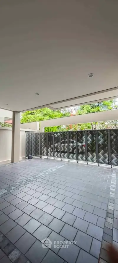 Spacious covered patio with modern tile flooring and privacy fencing, ideal for outdoor relaxation.