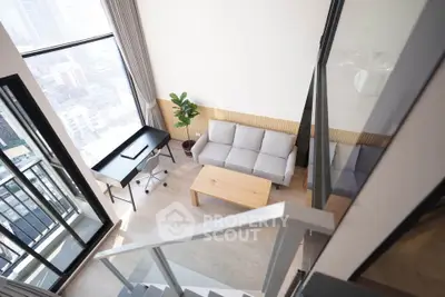 Modern loft-style living room with large windows and city view, featuring a cozy sofa and sleek desk.