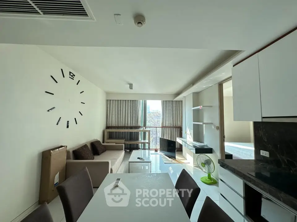 Modern living room with stylish decor and open layout, featuring a large wall clock and natural light.